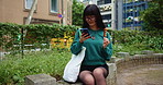 Japanese woman, park and typing with smartphone for social media, mobile notification and dango snack in city. Commuter, phone and search online for travel break, location or urban street of Tokyo