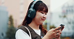 Woman, student and phone with headphones in city for thinking, schedule or travel to university. Person, girl and listen to music on smartphone, outdoor and mobile app for journey to college in Japan