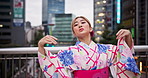 Japanese woman, outdoor or dancing for traditional performance, culture or freedom with energy in city. Asian girl, moving or dancer with art in kimono, rhythm or creative portrait on bridge in Tokyo
