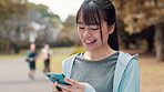 Laugh, fitness and Japanese woman with phone in park searching for online exercise program for health. Sports, cellphone and female athlete typing on browsing website for workout routine outdoor.