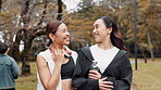 Fitness, friends and Japanese women in nature on break after workout for body health, wellness or chat. Happy team, exercise and girls talking at park for sports conversation, walking or water bottle