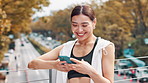 Happy, asian woman and laughing with phone for fitness, social media or break on bridge in city. Japanese, female person or runner with smile on mobile smartphone for funny joke, media or app in town