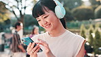 Asian woman, headphones and phone for music in city, online and scroll on social media in Japan. Female person, laughing and funny meme on internet for humor, hearing sound and comic podcast in town