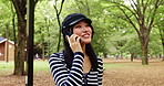 Japanese woman, nature and talking with phone call for communication, listening and gossip with contact. Park, female person and smile with mobile for conversation, vacation update and travel outdoor