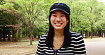 Face, hat and Japanese girl in park, smile and confidence with trees, wellness and calm. Portrait, Asian person and woman with stylish clothes, summer holiday and walking with happiness and outdoor