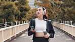 Asian woman, outdoor walking and headphones for exercise, thinking and streaming music in city. Female person, athlete inspiration and online for sound in Japan, fitness app and track cardio steps