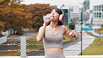 Morning, thirsty and woman with headphones, drinking water and hydration for runner, outdoor and wellness. Break, streaming and Japanese person with music, liquid and athlete with bottle in Japan