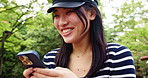 Japanese, woman and smile with phone at park for communication, reading notification and social media. Girl, laugh and mobile contact for texting, online blog and funny meme of nature travel in Japan
