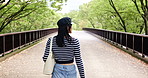 Japanese woman, back and walking at park outdoor for holiday, vacation or sightseeing trip with handbag. View, travel and female person at garden for journey, commute or tourist on road or bridge