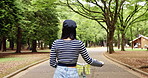 Walking, bike and back of Japanese woman in park for travel, carbon footprint and health. Eco friendly, transportation and summer with asian person and bicycle in nature for cycling and wellness