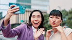 Selfie, friends and city with fun Japanese women, joy and social media with smile outdoor. Internet, happy and holiday with young professional on morning commute in Tokyo with silly hand sign and web
