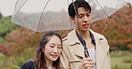 Park, umbrella and Asian couple in rain walking for commute, journey or travel outdoors. Dating, autumn and Japanese man and woman in conversation, bonding and talking with protection for water drops