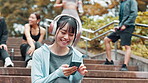 Break, texting and woman with smartphone, stairs and smile for message, online and athlete with app. Outdoor, typing and Japanese person with headphones, mobile and streaming of music in Japan