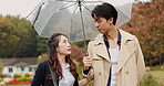 Walking, umbrella and Asian couple in park with rain for commute, journey and travel outdoors. Nature, autumn and Japanese man and woman in conversation with protection for drops, splash and water