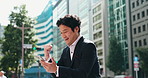 Business man, phone and celebration in city with fist, happy or success with notification for achievement. Person, smartphone and smile on travel for cheers, goal or announcement on sidewalk in Japan