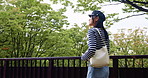 Japanese woman, travel and thinking outdoor at park for dream holiday, vacation or sightseeing trip. View, walk or Asian female person on journey, commute or tourist with handbag or phone on bridge