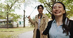 Holding hands, umbrella and Japanese couple in park for love, partner and bonding together. Commitment, walk and happy with asian man and woman on date in nature path for care, honeymoon and vacation