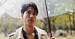 Thinking, umbrella and Asian man in park with rain for commute, journey and travel outdoors. Nature, winter and Japanese person walking with protection for drops, splash and water in cold weather