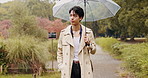 Walking, umbrella and Asian man in park with rain for business commute, journey and travel outdoors. Nature, winter and Japanese person with protection for drops, splash and water in cold weather
