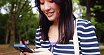 Japanese woman, typing and phone outdoor with communication, notification feedback and social media. Girl, smile and chatting with mobile for contact, texting and networking of nature travel in Japan