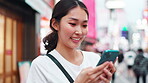 Woman, typing and smile with smartphone in city for online networking, text message and email response. Japanese person, phone and happy with internet search for travel location and urban town map