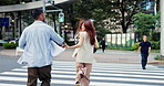 Japanese couple, back and holding hands with adventure in city, street and excited for travel and vacation or care. Man, woman and together with crosswalk, support and love on holiday in Tokyo