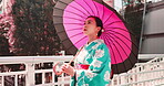 Woman, kimono and walking with umbrella in city, outdoor bridge and travel to Japan for peace. Female person, traditional clothes and relax in town for culture, local fashion and exploring urban