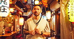 Night, happy man and travel in Japan for street food, journey and tourism in Omoide Yokocho for history. Tourist, walk and traditional kiosks in Tokyo for culture heritage, memory lane and experience