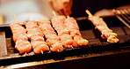 Chicken, food and skewers with heat for cooking, dining or meal prep of kebabs at restaurant. Closeup, japanese and chef hands with sticks for meat cuisine, snack or catering service at barbecue