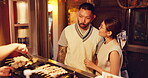 Night, order and couple in street for Asian food, dish choice or meal together at outdoor restaurant. Japanese people, waiting or option for kebab, snack or catering service on date in city in Japan