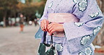 Woman, hands and kimono for fashion, culture and traditional Japanese style outdoor with fabric. Female person, bag and indigenous clothes for outfit, pride and confident with floral pattern in Tokyo