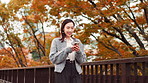 Business woman, phone and happy in park with texting, reading and mobile app on travel for work in city. Person, smartphone and smile with scroll, notification and social network on bridge in Japan