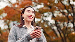 City, park and woman with phone, walking and search on path in maple trees on morning commute. Smartphone, smile and girl on outdoor adventure with mobile app, social media and urban travel in Japan