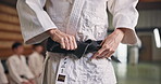 Martial arts, hands and tying black belt for sports, fitness and master ready for fight training in Japan. Aikido, knot and man with obi in dojo for exercise, preparation and wear uniform for workout