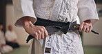Aikido, hands and tying black belt for sports, fitness and master ready for fight training in Japan. Martial arts, knot and man with obi in dojo for exercise, preparation and wear uniform for workout