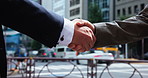 Business people, handshake and city with meeting for b2b, partnership or career opportunity. Closeup, employees or colleagues shaking hands on street sidewalk for deal, agreement or teamwork in town