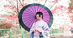 Woman, kimono and walking with umbrella of Japan, outdoor bridge and travel to park for view. Female person, traditional clothes and relax in nature for culture, local fashion and explore garden