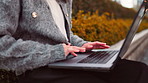 Woman, bench and hands with laptop outdoor with email, tech and working online with remote writing. Japanese, park and digital writer with creative project, typing and job in Tokyo with technology