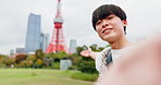 Influencer, selfie and Asian man by Tokyo tower in city for social media, video call or online vlog. Happy, travel and portrait of Japanese person for live streaming on holiday, adventure or vacation