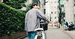 Man, back and bicycle in city for travel, location and building with adventure, commute or trip. Asian person, walking and bike in urban town for eco friendly transport, exercise or morning in Japan
