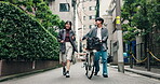 Couple, talking and walking with bicycle in street for morning commute, urban journey and laughing. Japanese people, happy and together with bike in city in town for travel, conversation and support