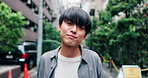 Travel, happy and face of Asian man in city with smile for holiday, adventure and weekend outdoors. Relax, urban town and portrait of person in road with pride on commute, trip and vacation in Japan