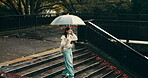 Walking, steps or Asian woman in city with umbrella in park in Japan culture for tourism. Rain protection, girl or Japanese person in urban town for travel or sightseeing on outdoor holiday adventure