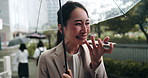Voice, phone call and woman in city with umbrella, business discussion and morning commute in winter. Rain, cover and Japanese businesswoman with smartphone speaker, communication and urban travel