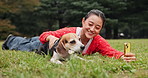 Woman, dog and happy for video call at park, snack and love with phone, excited and relax on lawn. Person, animal and pet beagle puppy with food, lying and reward with mobile app on grass in Japan