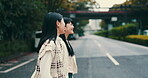 Women, walking and cross street in town of Japan, speaking and friends travel together in city. People, conversation and adventure or urban journey on road, relax and outdoor hangout for bonding trip