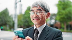 Business man, smartphone and texting in city on travel, contact and scroll with smile on mobile app. Mature person, outdoor and phone on commute to workplace with notification, chat or email in Japan