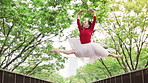 Woman, ballerina and dancer with jump on bridge, moving and low angle in urban park for performance in spring. Person, dancing and outdoor with steps, creativity and talent for street art in Japan