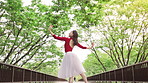 Woman, ballet and dancing with smile on bridge, moving and low angle in urban park for performance in spring. Person, dancer and outdoor with steps, creativity or happy for talent with art in Japan