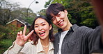 Japanese couple, selfie and kiss for love, social media and profile picture outdoor with peace sign. Man, woman and happy Asian people for photography, bonding and valentines day with memory or face